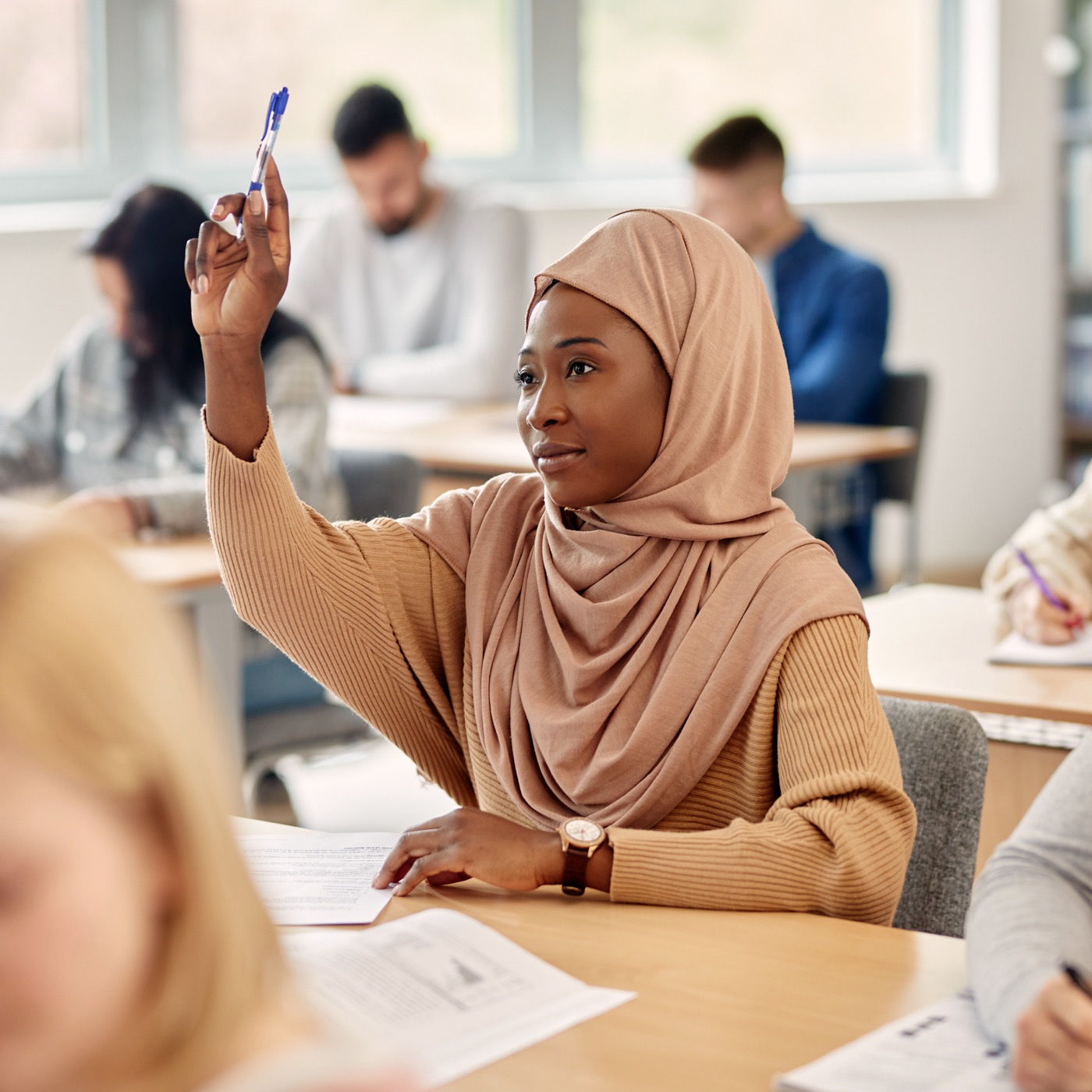 Student raising their hands in class