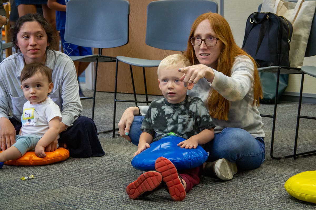 Parent pointing with child in her lap