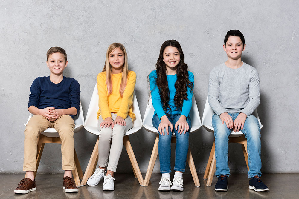 a photo of four students sitting in chairs against a wall