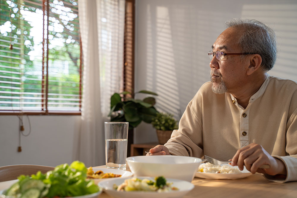 asian older man eating alone at a table