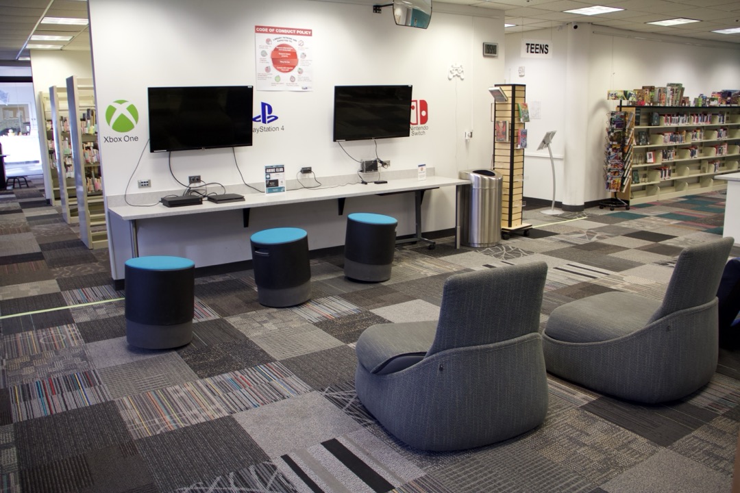 Photo of Teen Game Center within the 21c Library showcasing two tvs and some game consoles