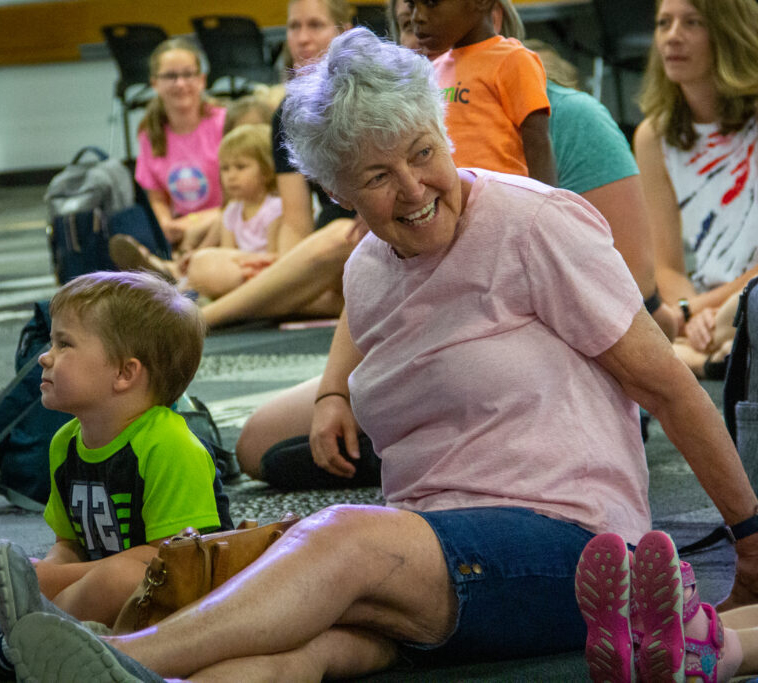 Parents sitting on the ground with their children at a library event