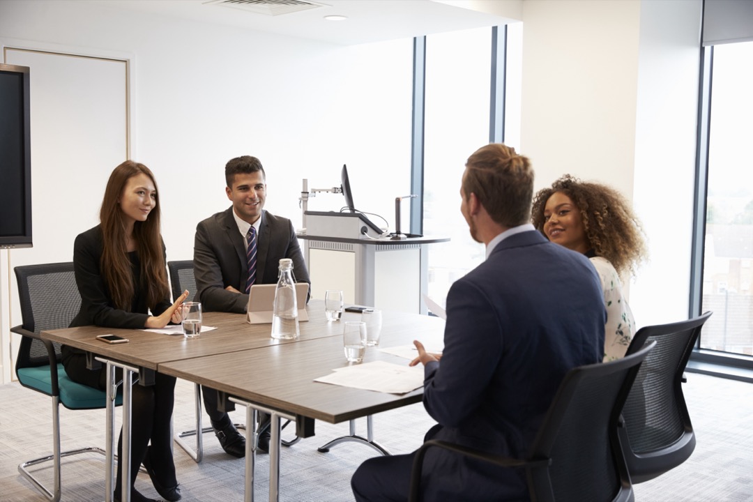 An interview going on with four people wearing suits