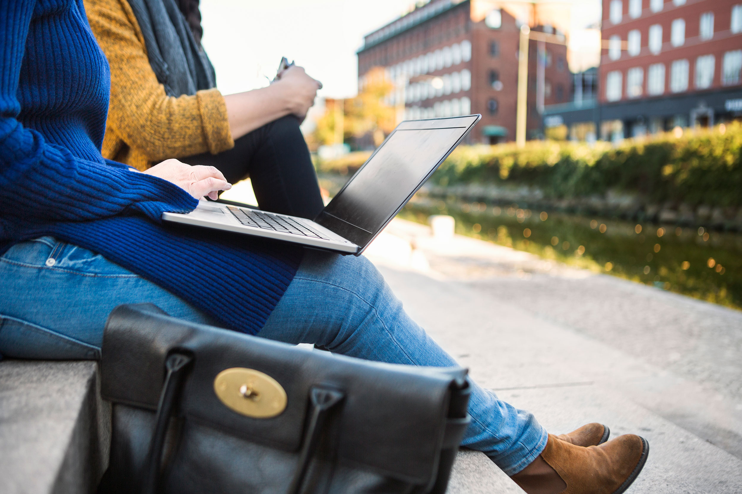 Two women sitting outside using a laptop