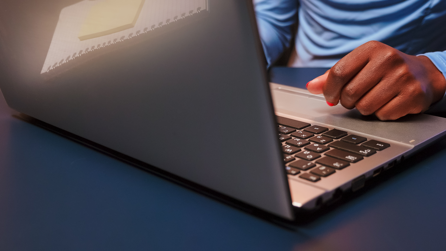 close up of a black woman using a laptop on a desk