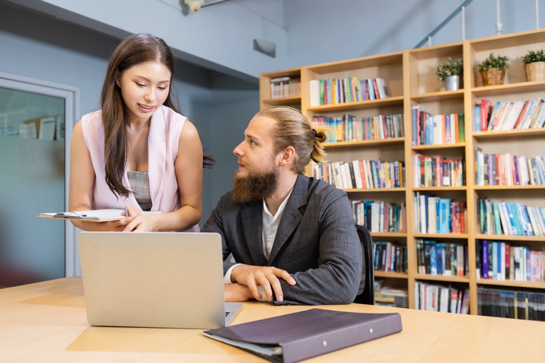 A Librarian helping a patron on his computer