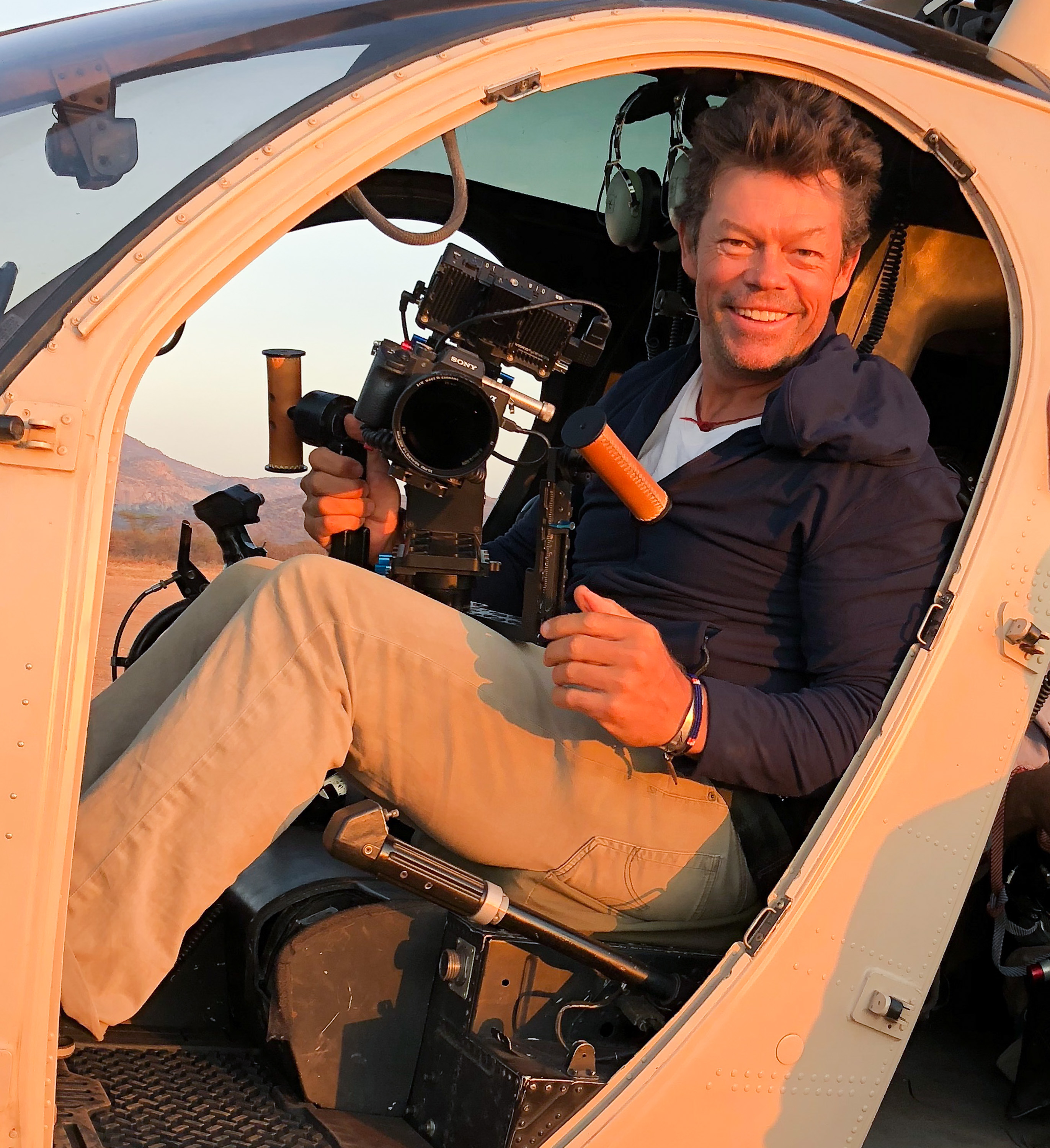 Pete McBride photographed in a helicopter holding a camera 