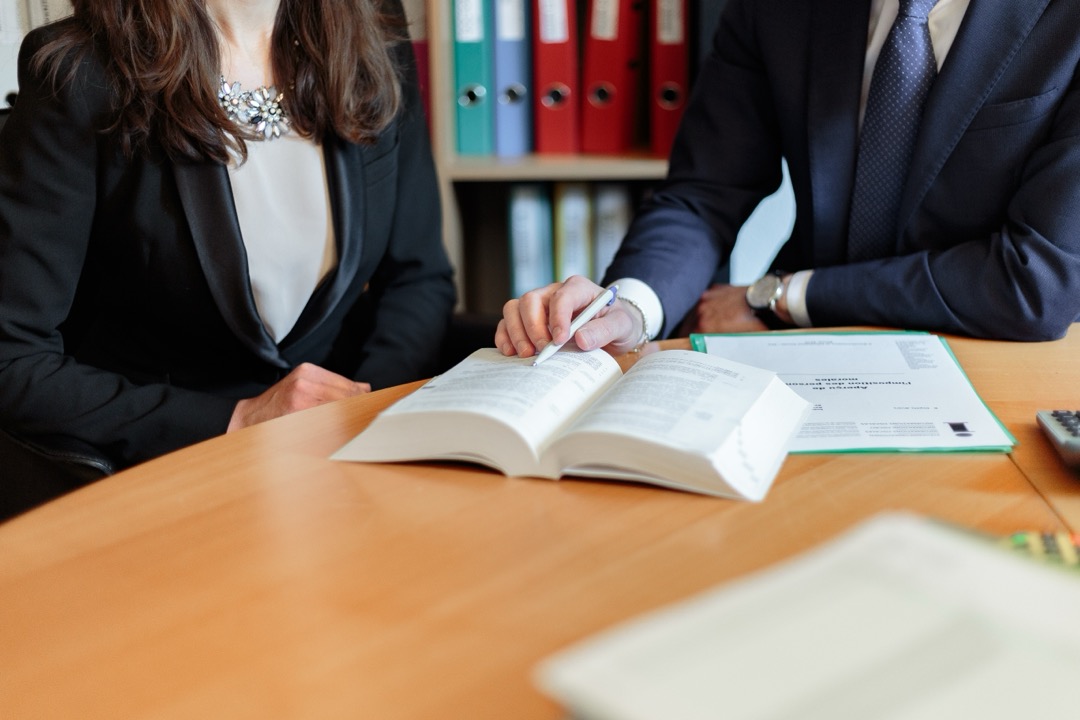 two people discussing a chapter within a book on the table