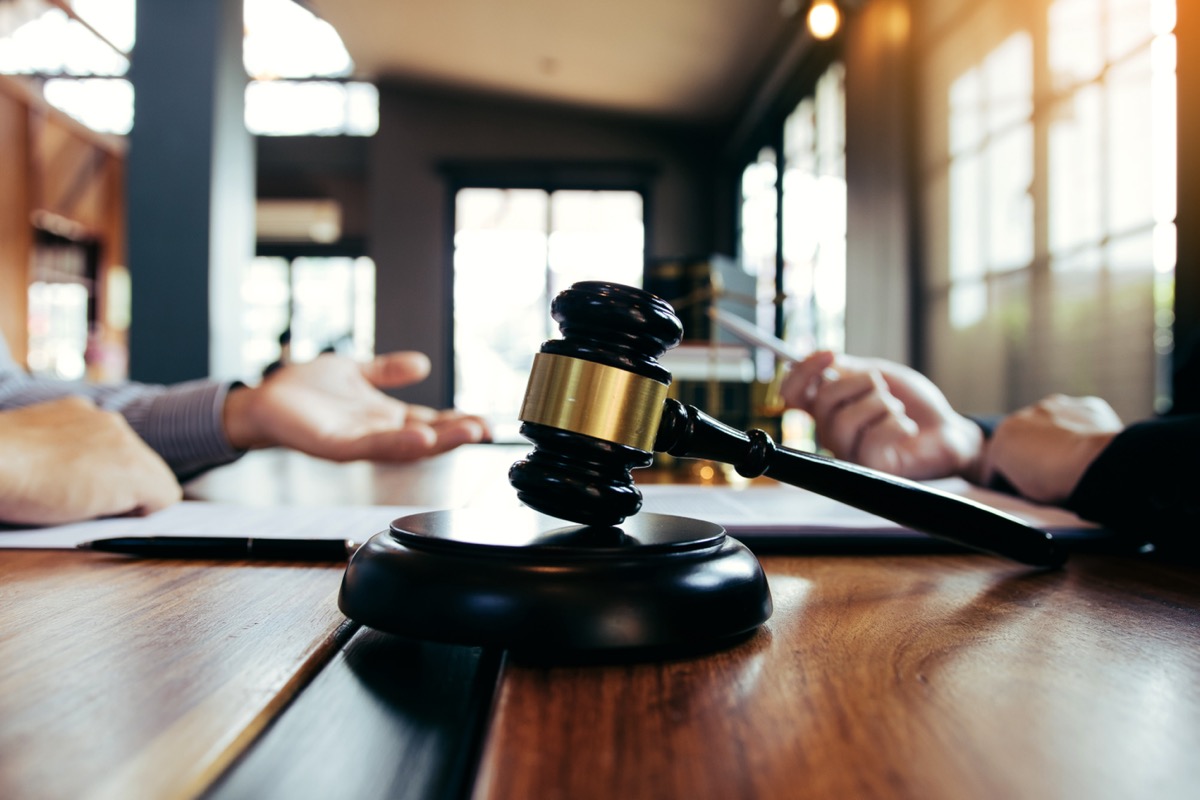 People talking in a meeting with a closeup shot of a gavel sitting on the table
