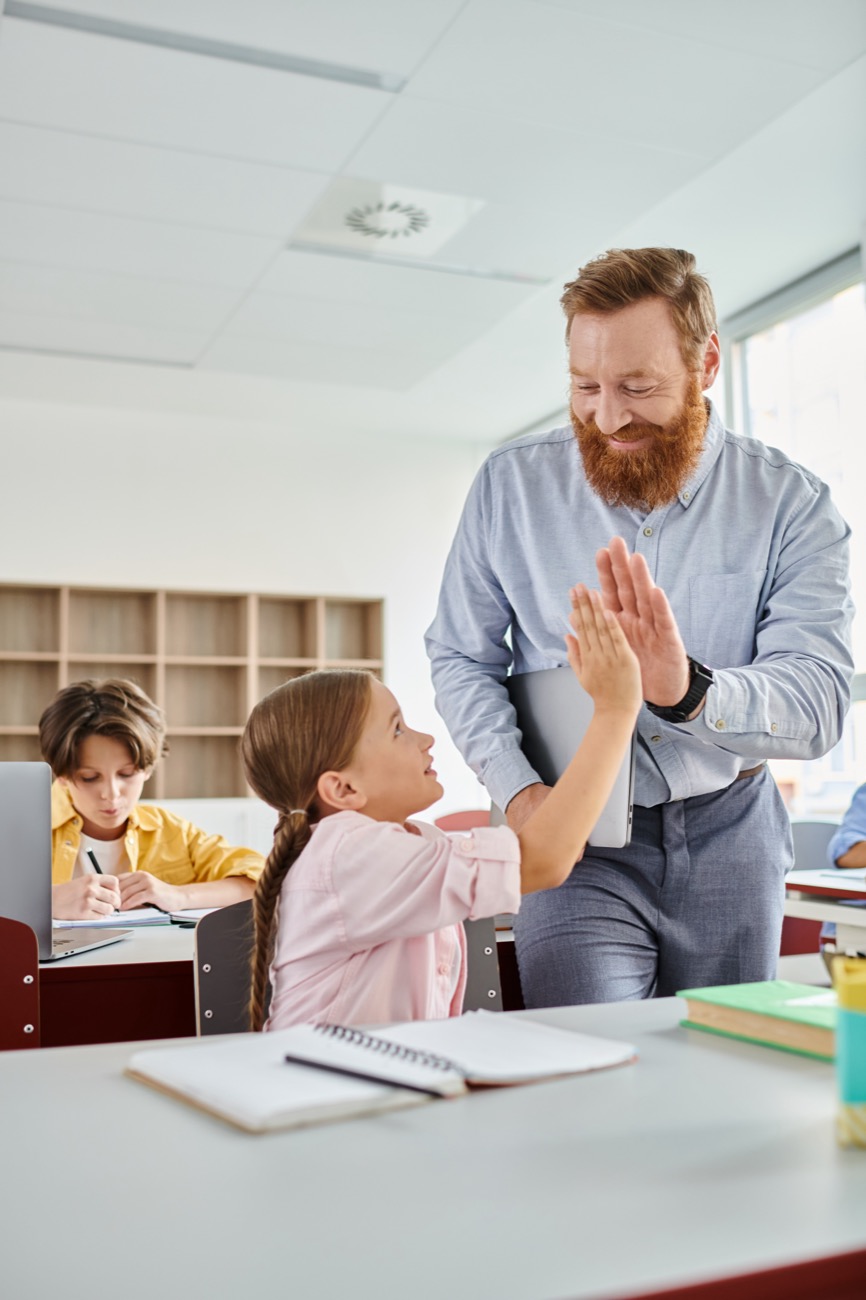 Teacher High-fiving a first grade girl in a school classroom
