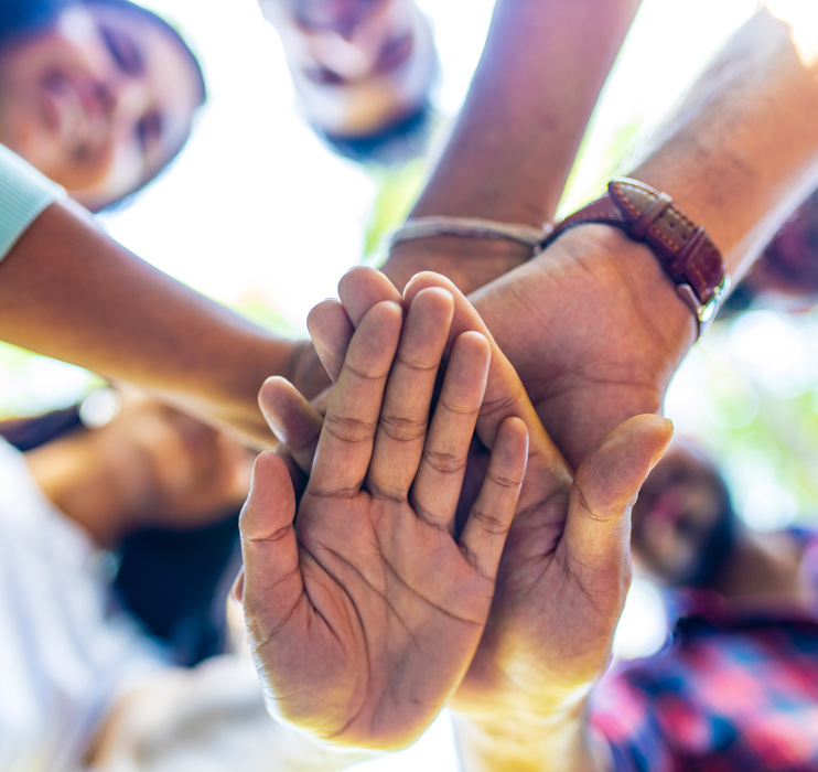 A close up photo of people holding their hands together in a team