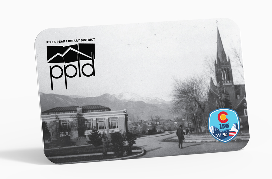 A Library Card sitting on a grey table with an old photo of colorado springs on the front of the card