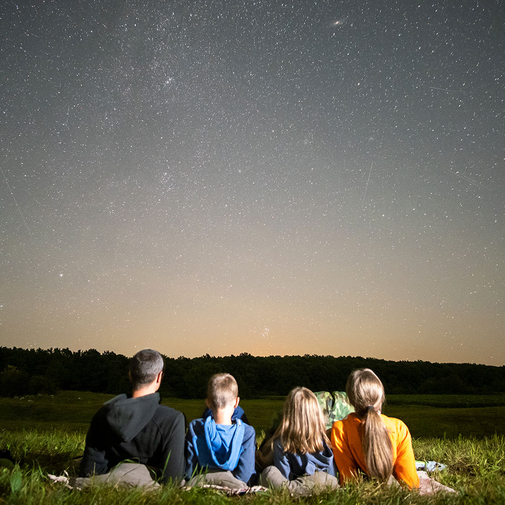 a family laying in a field looking at the stars