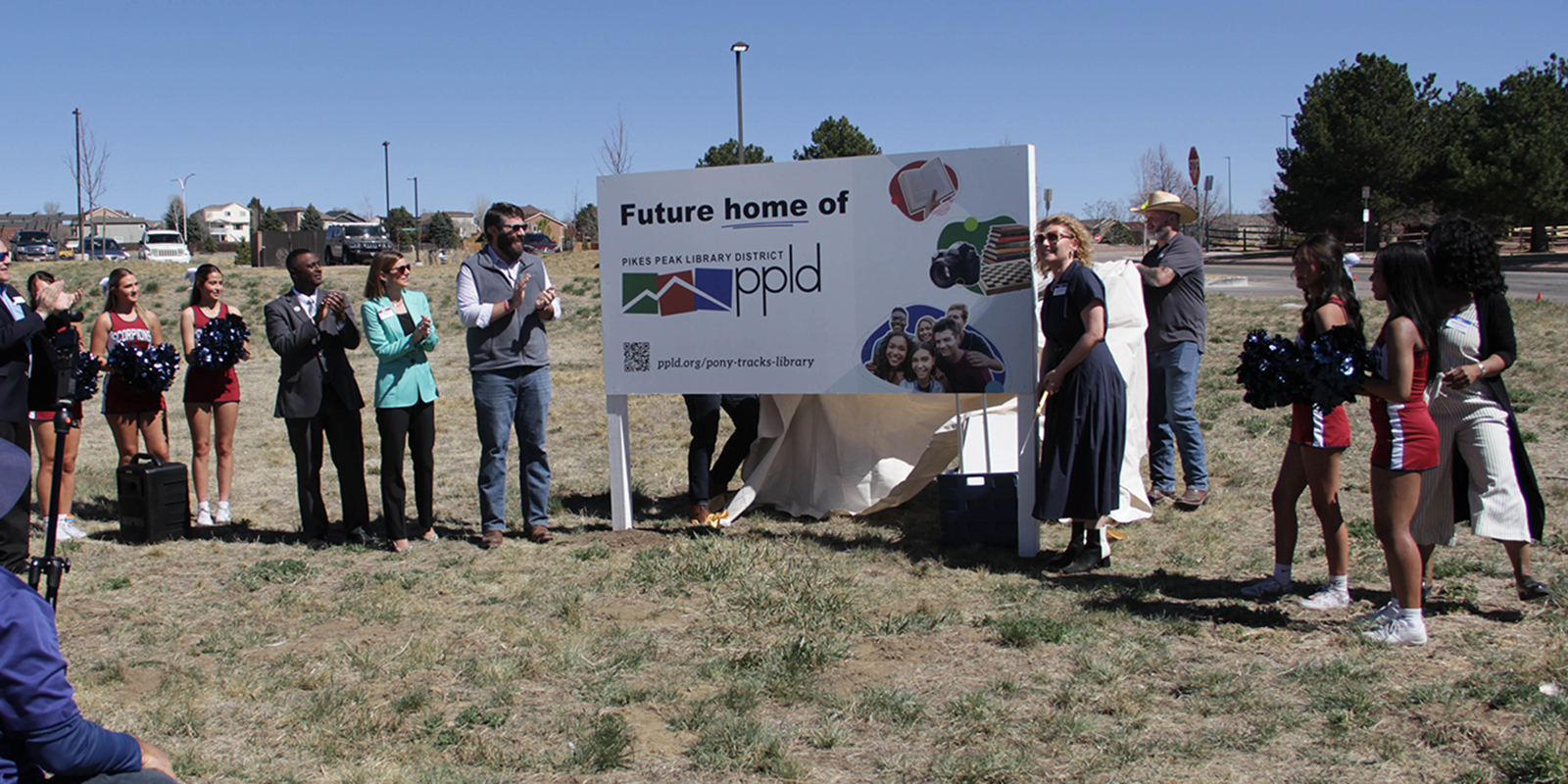 Teona Shainidze Krebs standing in front of a sign that says "Future Home of PPLD" Celebrating the purchase for the property for the new Pony Tracks Library
