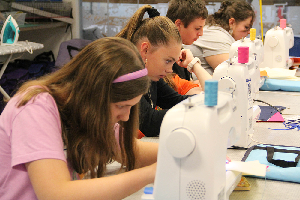 four teens participating in a sewing class in the makerspace