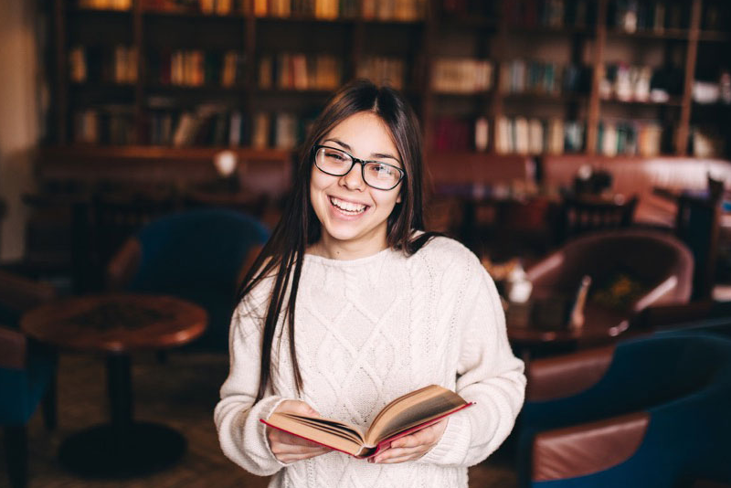 Student holding a book in a library