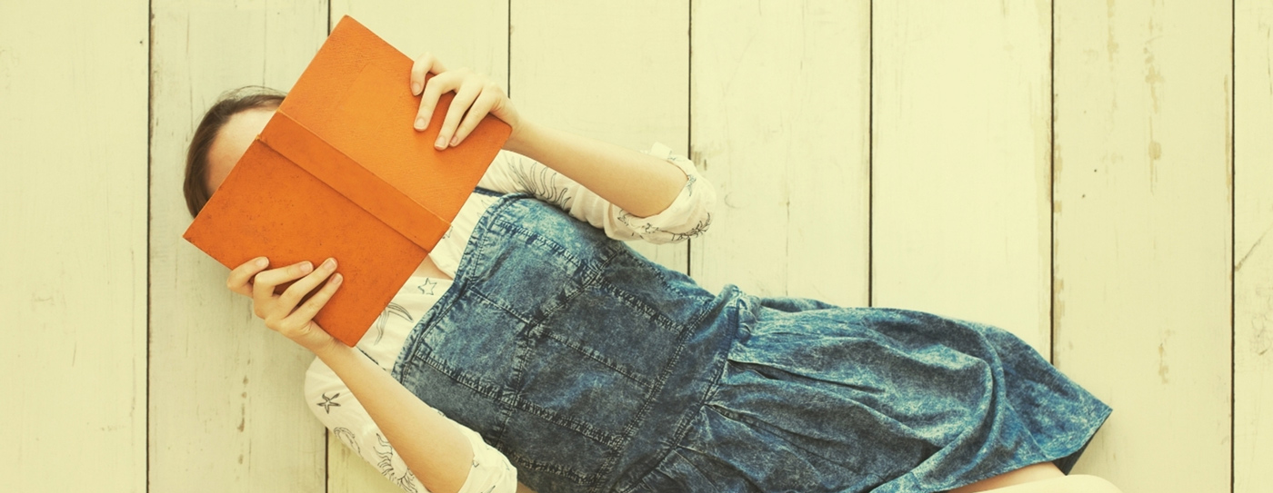 Kid laying on their back reading a book