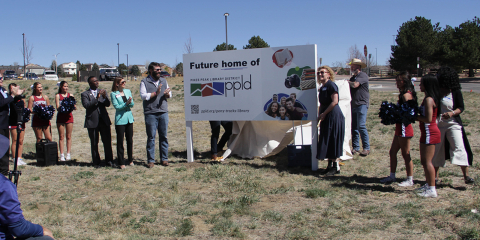 Teona Shainidze Krebs standing in front of a sign that says "Future Home of PPLD" Celebrating the purchase for the property for the new Pony Tracks Library