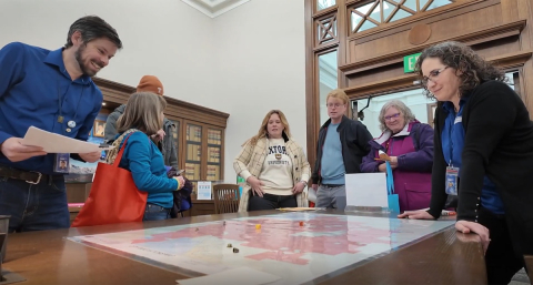 A group of people playing a Board game at the Regional History and Genealogy Open house