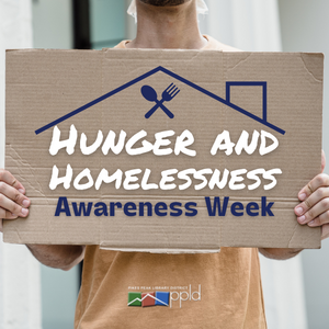 A person holding a cardboard sign that reads "Hunger and Homelessness Awareness Week."