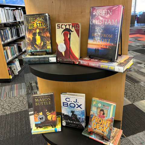 A selection of several top books from 2023 sit on a book display, including The Sun and the Star; Scythe; The Boys from Biloxi, Front Desk, and others.