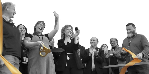 A group of Library Staff gathered together cutting the ribbon for the Manitou Springs Reopening