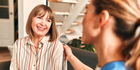 A women smiling while another woman rests her hand on shoulder